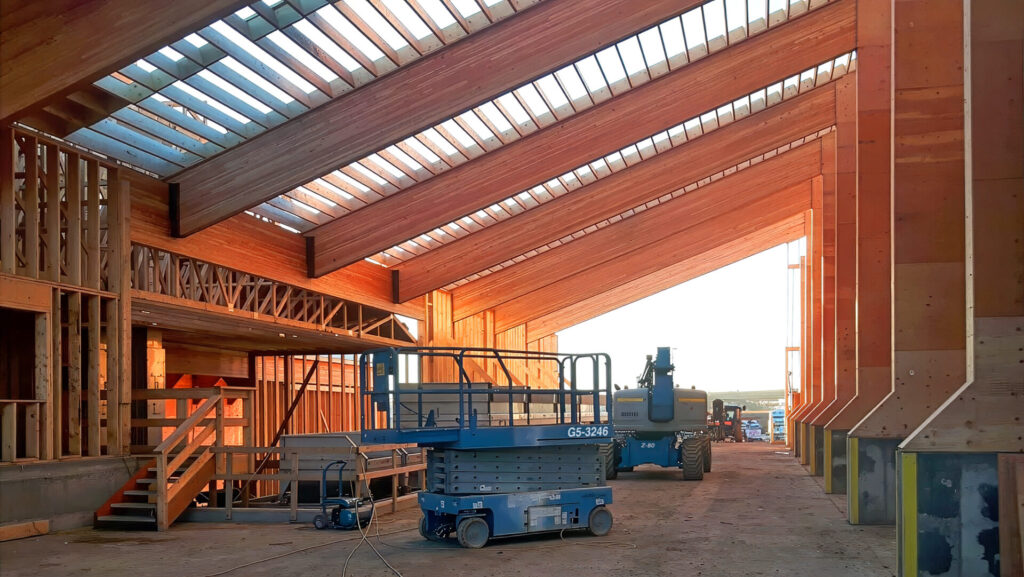 Looking up at large exposed wooden pillars and beams from a Northern Legendary Construction Ltd. project while it was underway in Dawson Creek, BC.