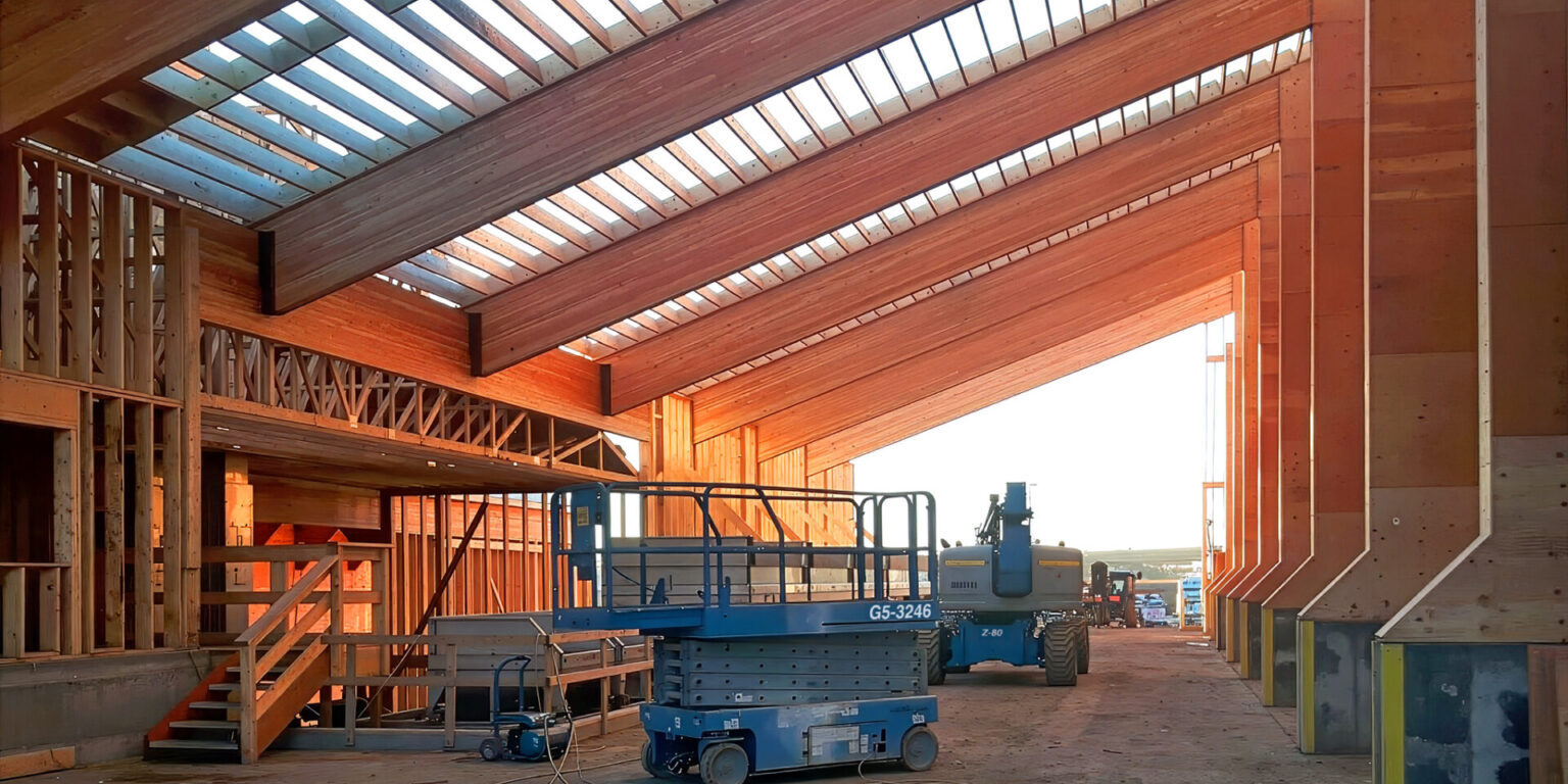 Looking up at large exposed wooden pillars and beams from a Northern Legendary Construction Ltd. project while it was underway in Dawson Creek, BC.